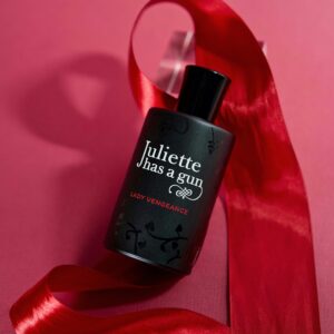 Sophisticated perfume bottle with a red ribbon on a pink background, highlighting elegance and luxury.