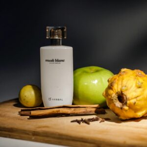 Elegant arrangement of perfume and fruits on wooden board, ideal for still life themes.