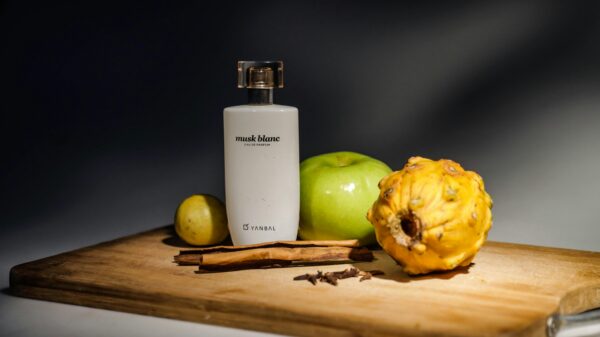 Elegant arrangement of perfume and fruits on wooden board, ideal for still life themes.